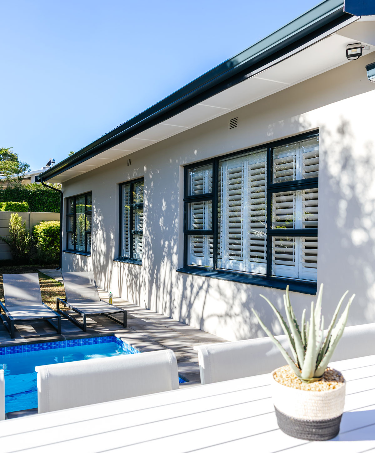 Charcoal shutters on a home exterior beside a pool